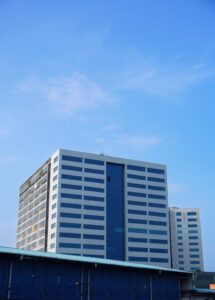 A tall office building in Kochi, India with a bright blue sky background.